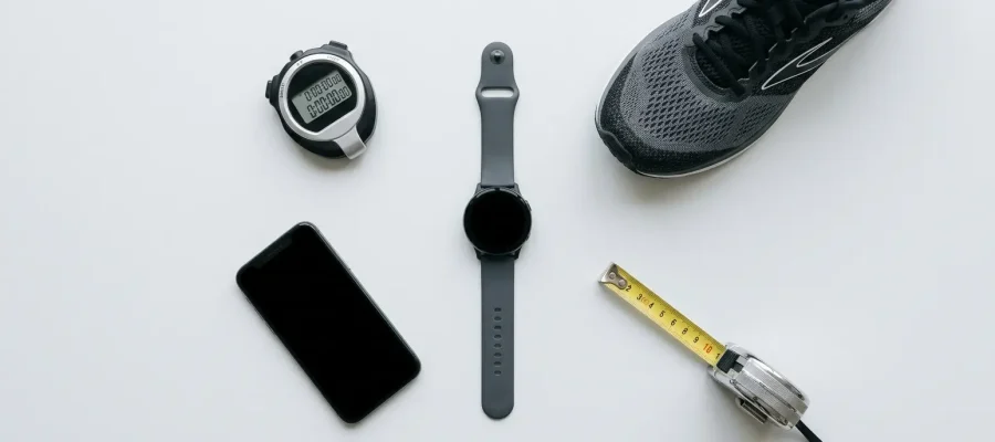 a stopwatch, a running shoe, a phone, a tape measure — arranged around a generic smartwatch